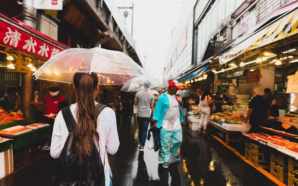 雨の中市場を歩く女性
